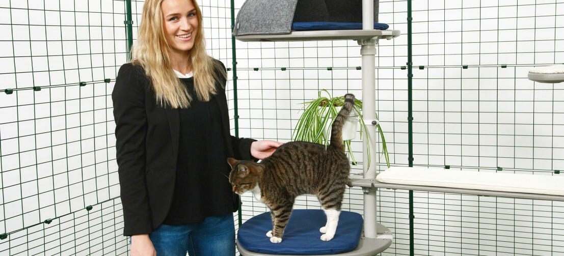 Flicka klappar sin katt som leker på Freestyle kattträd utomhus