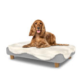 Hund sitter på en medium Topology hundbädd med fårskinnsöverdrag och runda träfötter