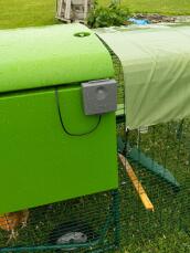 En kontrollpanel för en automatisk dörr till en hönsgård som är placerad på sidan av en plasthönsgård.
