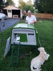 Man med hund och Omlet grönt Eglu Cube stort hönshus och springa