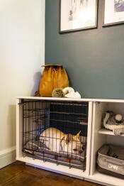 En vit hund som sover i en Fido Nook med en garderob och en låda.