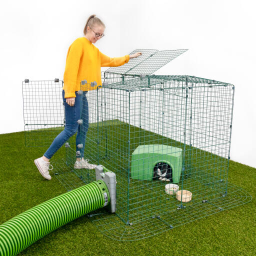En flicka öppnar en del av en djurhage med kaniner i ett skyddsrum med en Zippi hage.
