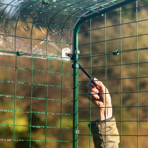 En hand som fäster locket på walk in run med bungee-krokar