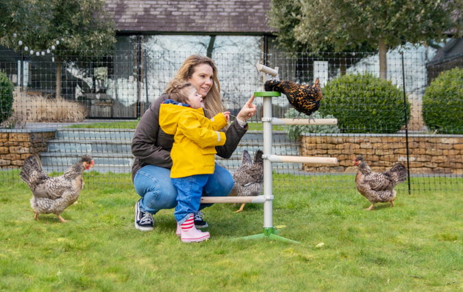 mamma och dotter i trädgården leker med sina höns